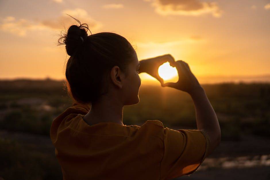 吸引力法則完整教學A silhouette of a young woman forming a heart shape at sunset in Kelâat M'Gouna, Morocco.