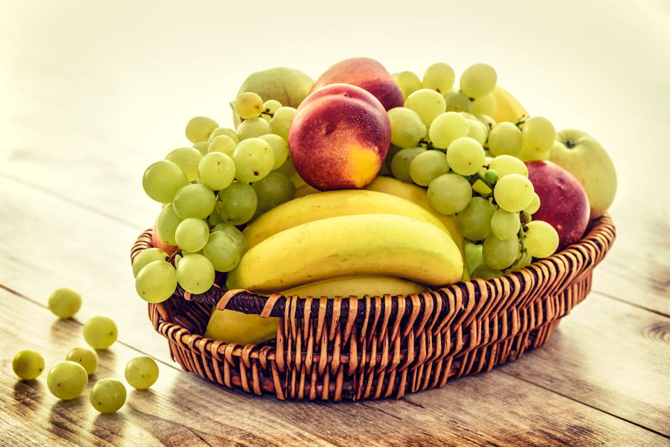 菩薩生日準備哪些供品?A colorful wicker basket filled with fresh grapes, bananas, and apples on a wooden table.