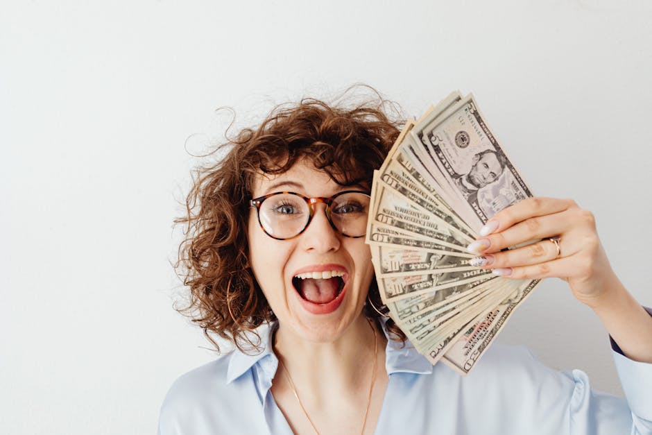 量子與吸引力法則：高效掌握量子意識，創造富足人生 Caucasian woman with curly hair delights in holding US dollars against a white background.