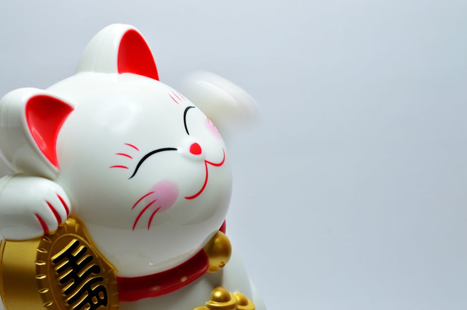 量子與吸引力法則：高效掌握量子意識，創造富足人生 Close-up of a white Maneki Neko figurine with a raised paw symbolizing luck and fortune.