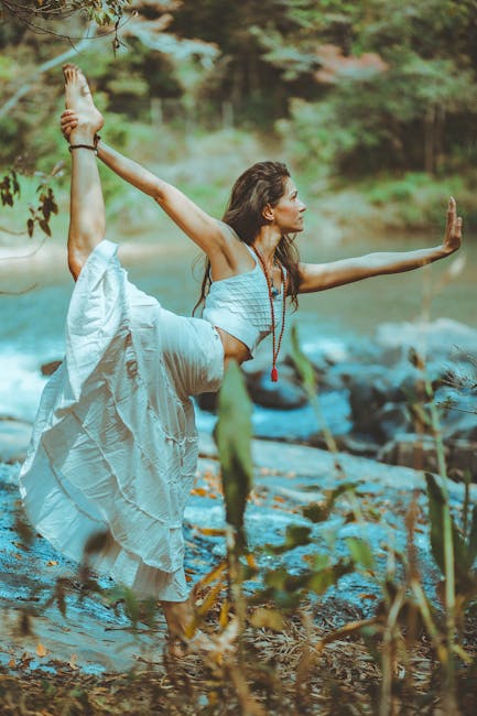 脈輪瑜伽:核心力量的啟動A serene scene of a woman practicing yoga by a picturesque river shore, embodying balance and tranquility.
