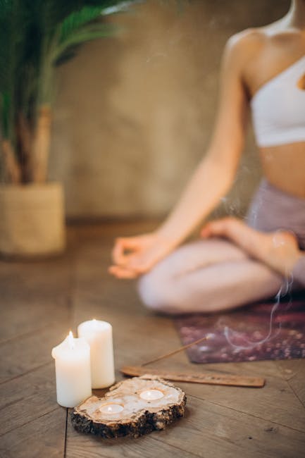 脈輪瑜伽:芳療瑜珈的能量之旅Woman practicing meditation in lotus pose with candles and incense, focusing on wellness and relaxation.